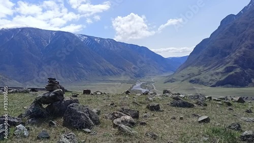 A group of stone pyramids on top of a high cliff overlooking a picturesque valley in the mountains on a sunny spring day. Chulyshman river valley, Altai, Siberia, Russia.