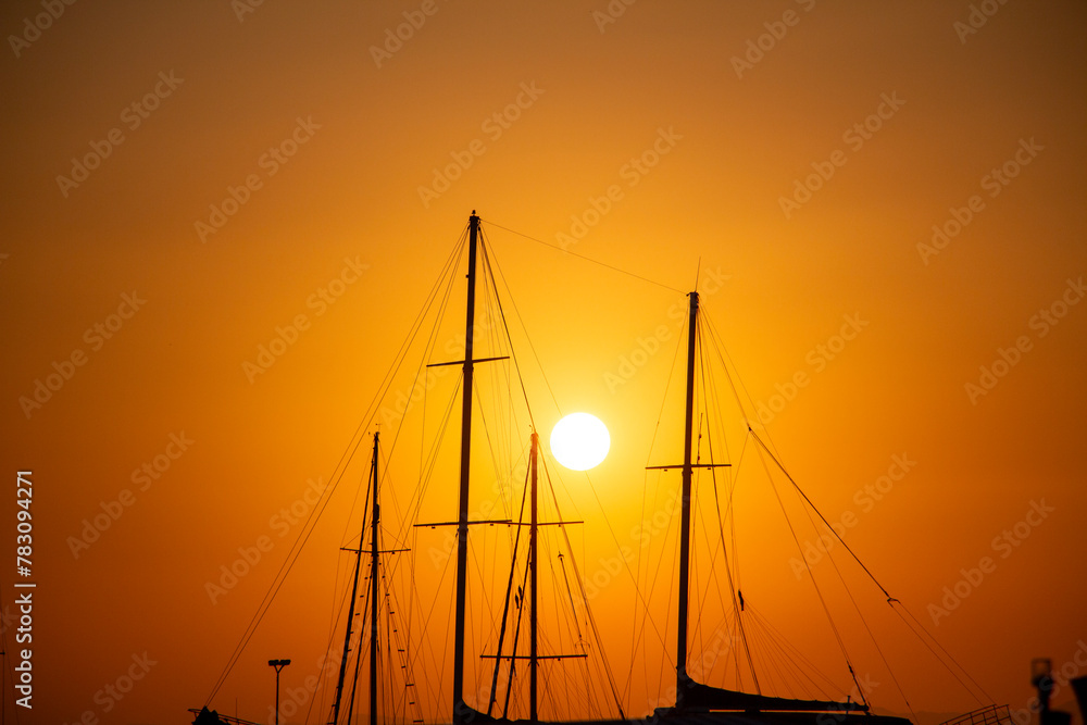Silhouette of yachts at sunset in the harbor. Silhouette of a sailboat at sunset in the sea.