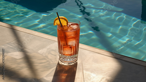 photo of cocktail next to a pool, on concrete, sunlight creating shadows through the glass 