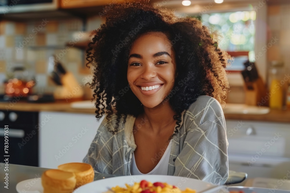 Smiling young woman eating breakfast at table in kitchen