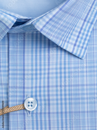 Close-up of a button placket on a plaid shirt with blue undertones