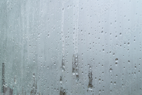 The window is foggy and has water droplets on it. Scene is cold and damp