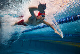 Water bubbles demonstrating speed. Young man, swimming athlete in motion in pool training, preparing for competition. Concept of professional sport, health, endurance, strength, active lifestyle