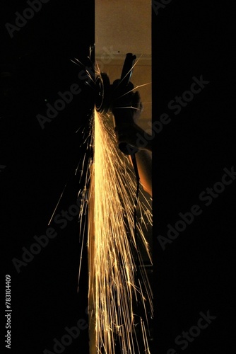 Main d'un ouvrier travaillant le métal et produisant des étincelles en meulant. On voit ses mains de travailleur d'industrie qui se détachent sur fond noir photo