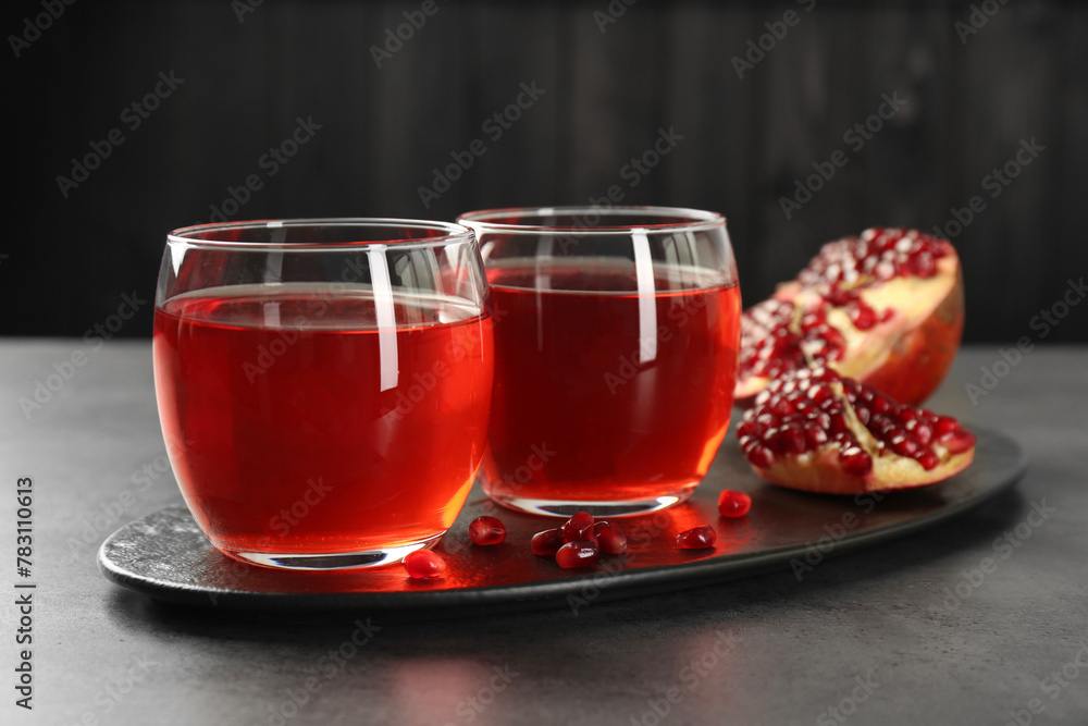 Tasty pomegranate juice in glasses and fresh fruit on grey table Tasty pomegranate juice in glasses and fresh fruit on grey table