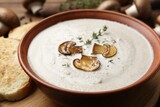 Fresh homemade mushroom soup in ceramic bowl on wooden table, closeup
