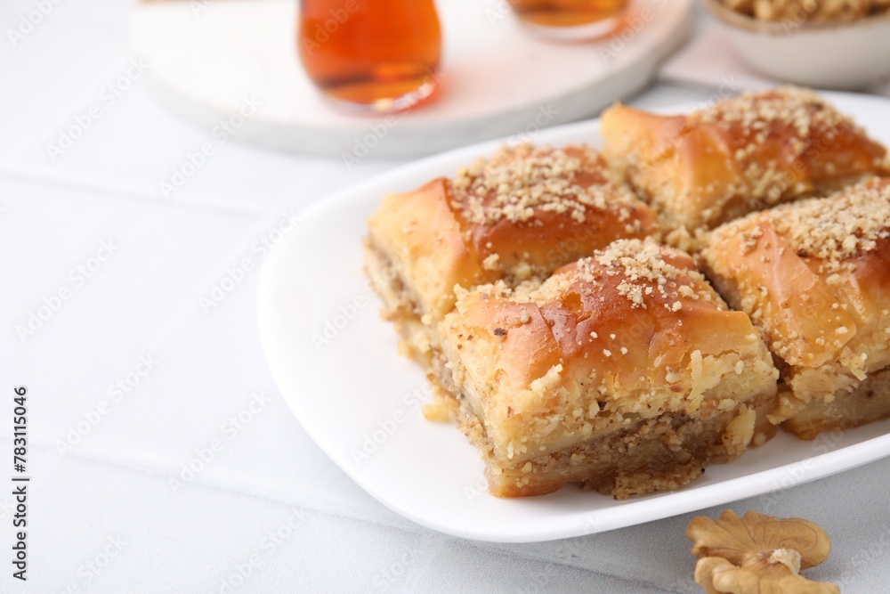 Eastern sweets. Pieces of tasty baklava and tea on white tiled table, closeup. Space for text