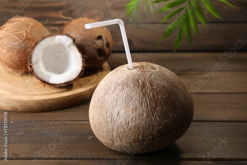 Coconut water. Fresh nut with straw on wooden table