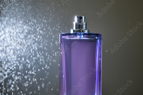 Perfume spray in a violet bottle on a dark background.