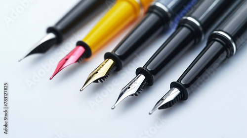 Assorted fountain pens with different nibs and colors arranged in a row on a white background.