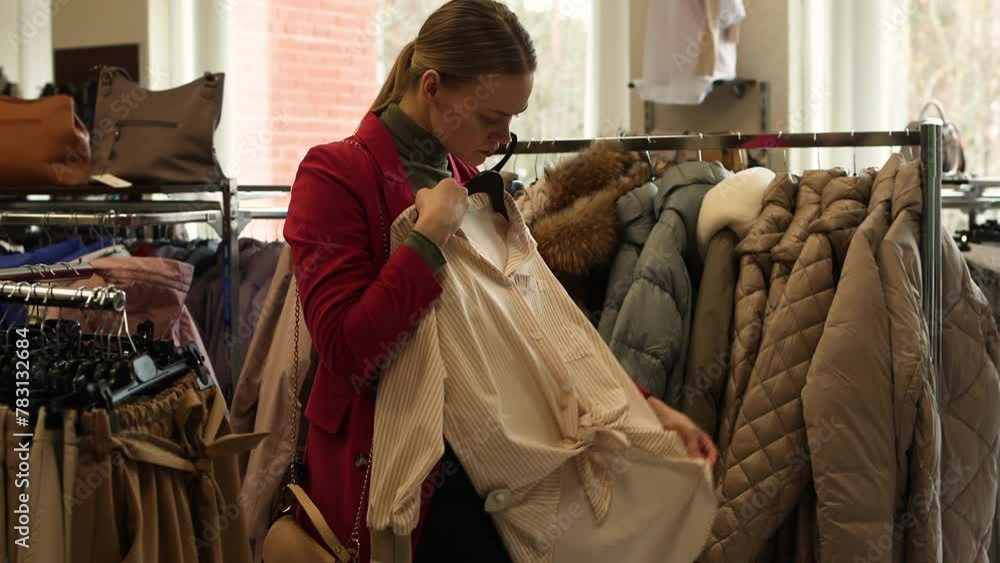 Woman is shopping for casual clothes fashionable women's clothing store, in boutique inspecting differents blouses price tags and the quality of fabric. Shopping in Clothing Store. Woman is shopping for casual clothes fashionable women's clothing store, in boutique inspecting differents blouses price tags and the quality of fabric. Shopping in Clothing Store.