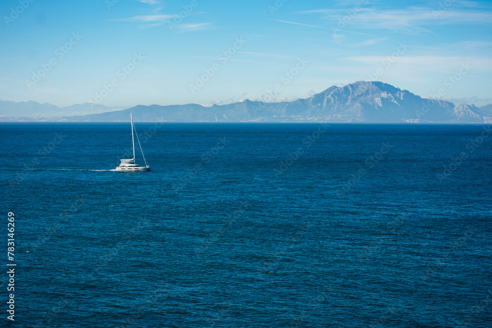 sailboat sailing the waters of the Alboran Sea, with the mountains of the African continent in the background.