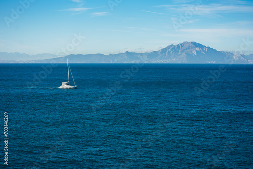 sailboat sailing the waters of the Alboran Sea, with the mountains of the African continent in the background.