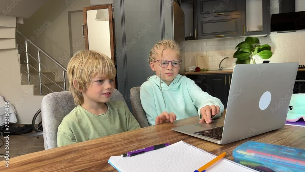 Online school class, siblings pupils boy and girl learning together remotely online at home, looking to laptop, speaking with teacher or tutor using internet Online school class, siblings pupils boy and girl learning together remotely online at home, looking to laptop, speaking with teacher or tutor using internet