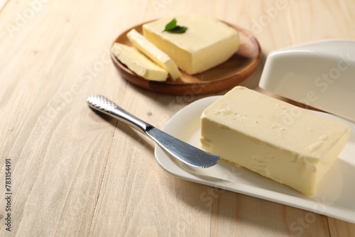 Tasty butter and knife on wooden table
