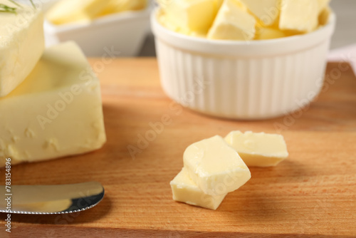Pieces of tasty butter on wooden board, closeup
