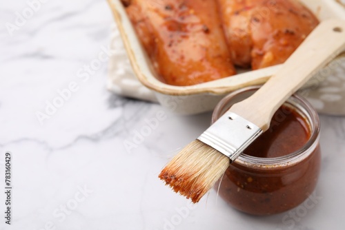 Bild auf Leinwand Fresh marinade, basting brush and raw chicken fillets on white table, closeup