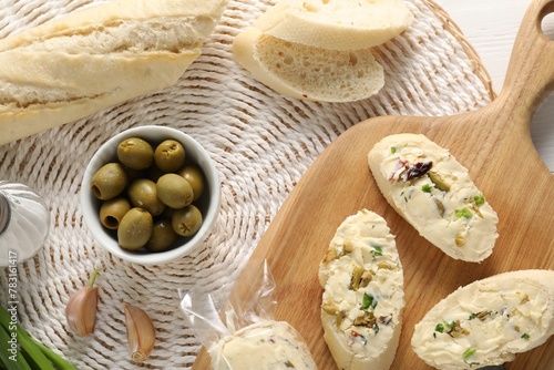 Tasty butter with olives, green onion, garlic and bread on table, top view