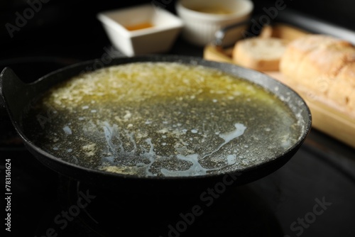 Melted butter in frying pan on black table, closeup