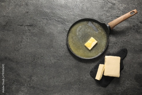 Melting butter in frying pan and dairy product on grey table, top view. Space for text photo