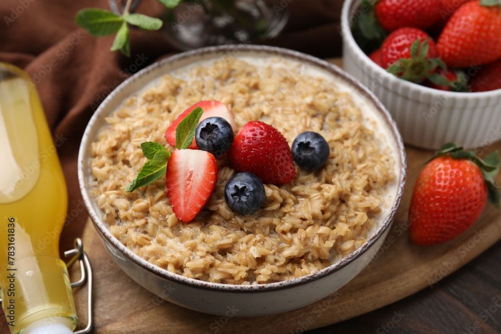Tasty oatmeal with strawberries and blueberries in bowl on wooden table, closeup Tasty oatmeal with strawberries and blueberries in bowl on wooden table, closeup