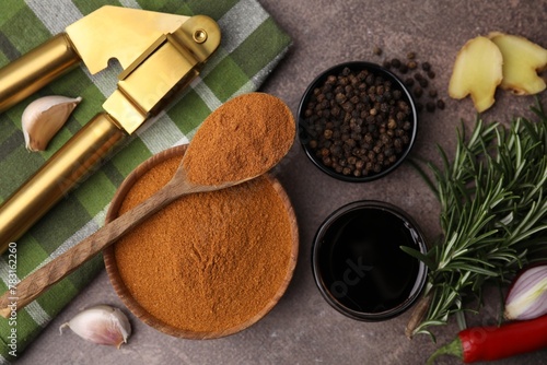 Aromatic spices, fresh ingredients for marinade and garlic press on brown table, flat lay