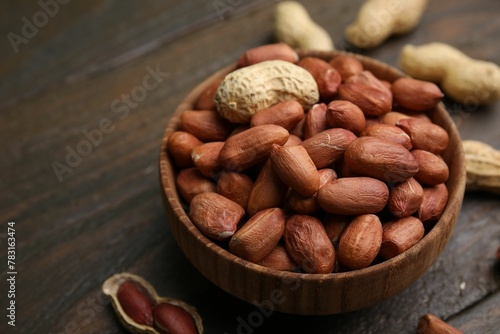Fresh peanuts in bowl on wooden table, closeup. Space for text