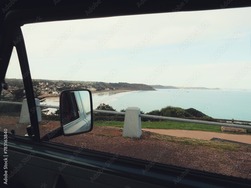 Mirror of the van with the sea and the coast in the background.