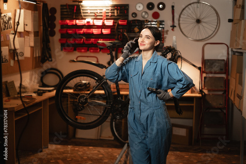 young beautiful brunette woman standing alone in his bicycle shop and using technology.