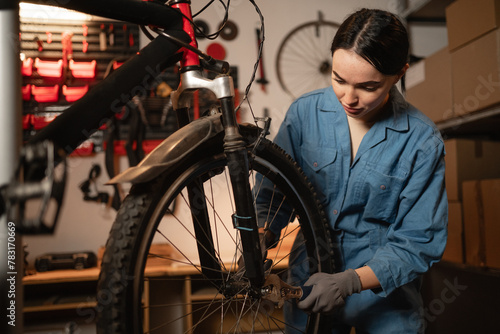 Young female repairing a bicycle in a bike store. Bike workshop interior.