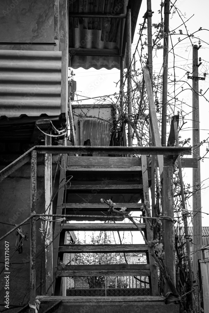 Metal stairs to the second floor of an old abandoned house, black and white photo, gloomy photo