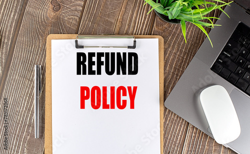 REFUND POLICY text on clipboard paper with laptop, mouse and pen photo