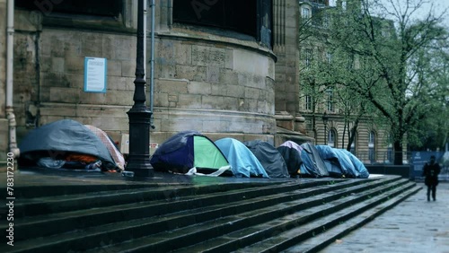 Many tents of migrants and homeless people in the rain in the street of Paris, France