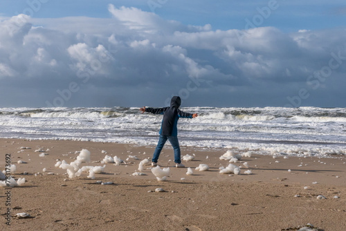 Junge an einem Nordseestrand bei Sonne und Sturm