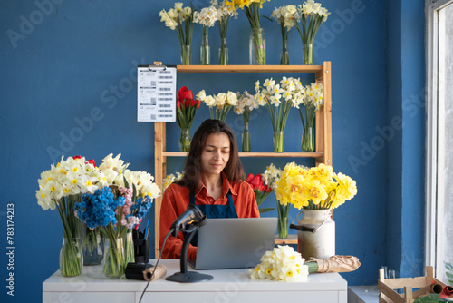 Hispanic Woman florist small business flower shop owner, using her laptop to take orders for her store.