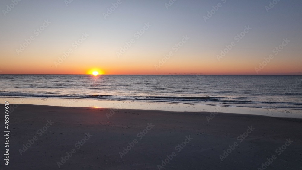 Beautiful morning sunrise over the ocean at the beach with warm sunlight shining on peaceful sea with calm gentle surf and waves at Pawleys Island, South Carolina low country lifestyle by the seashore