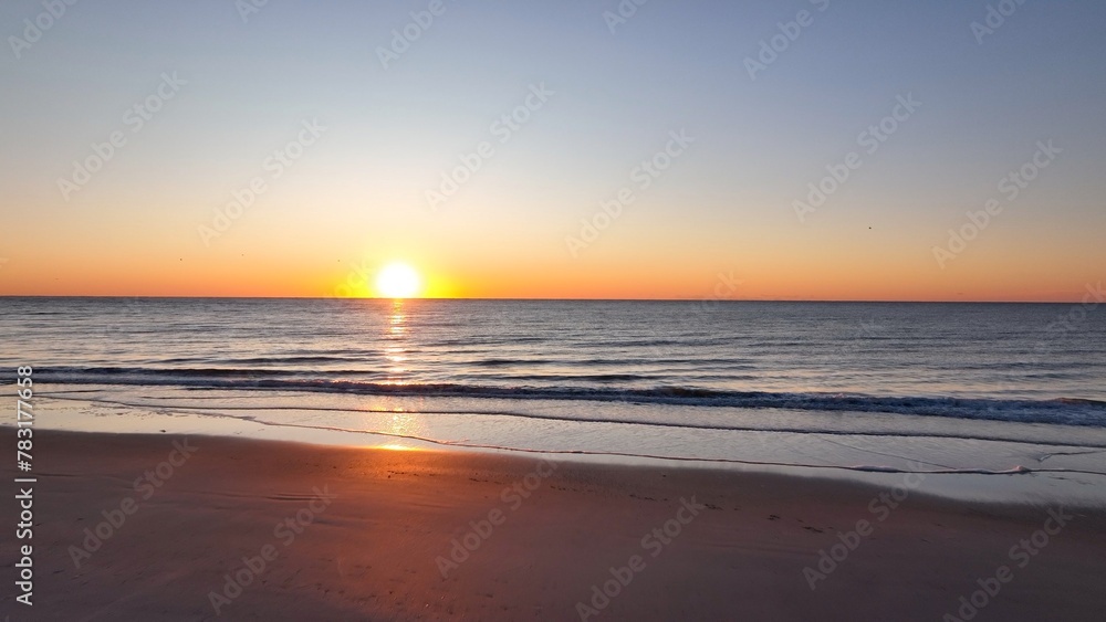 Beautiful morning sunrise over the ocean at the beach with warm sunlight shining on peaceful sea with calm gentle surf and waves at Pawleys Island, South Carolina low country lifestyle by the seashore