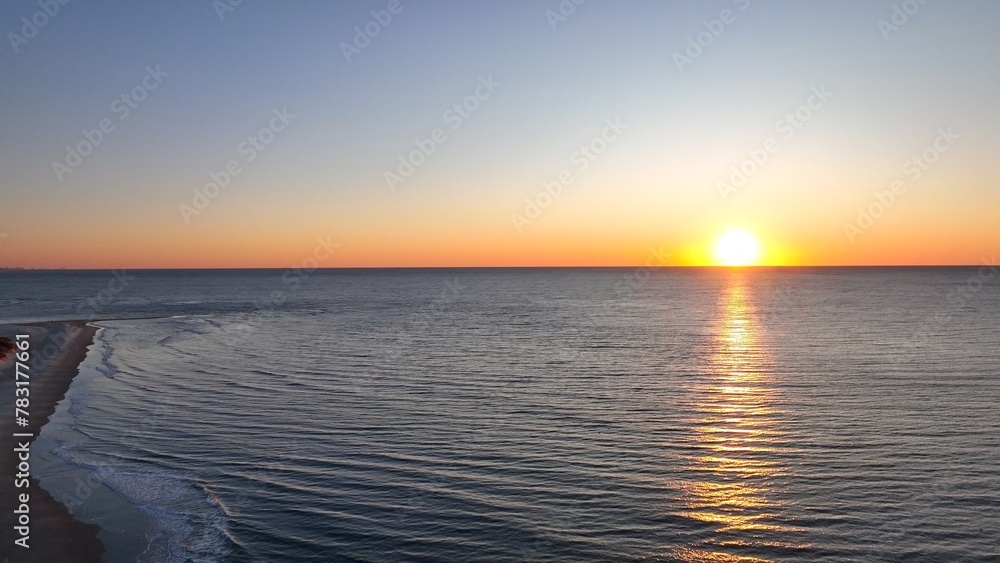 Obraz premium Beautiful morning sunrise over the ocean at the beach with warm sunlight shining on peaceful sea with calm gentle surf and waves at Pawleys Island, South Carolina low country lifestyle by the seashore