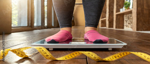 Close-up and bottom view of an overweight girl using scales in front a measuring tape on wooden floor. Obesity, overweight and eating disorders concept. Generative Ai. photo