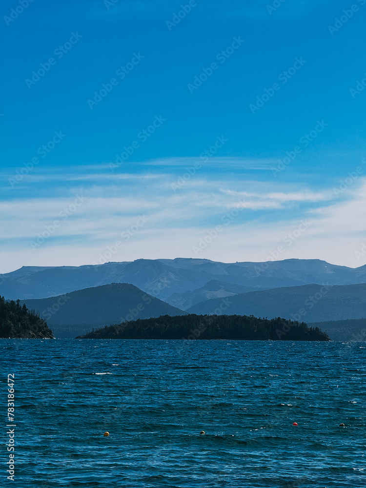 A beautiful blue ocean with mountains in the background. The sky is clear and the sun is shining