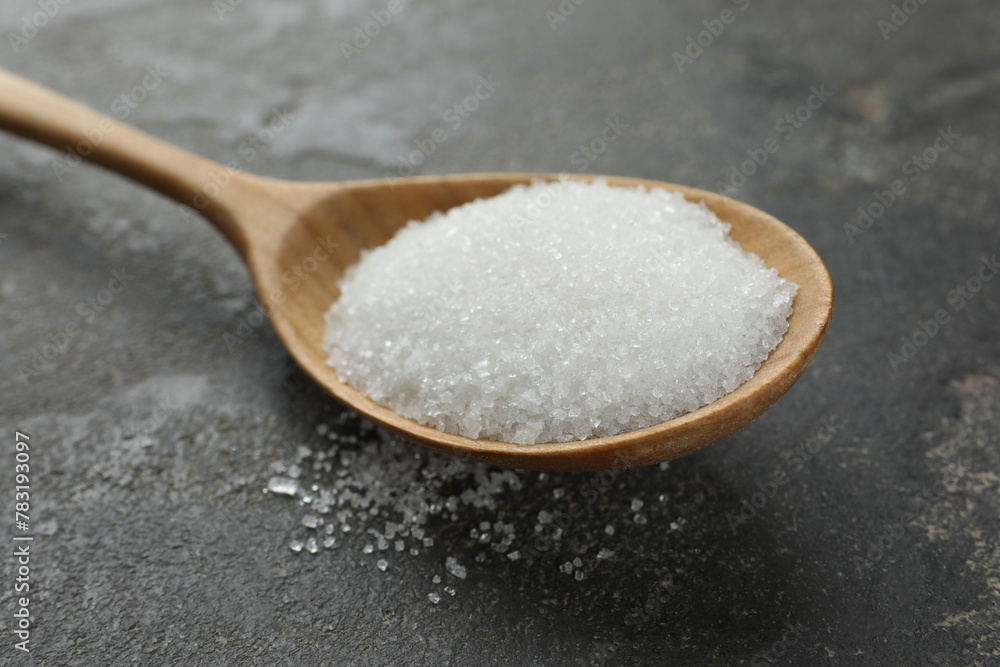 Spoon with granulated sugar on grey textured table, closeup Spoon with granulated sugar on grey textured table, closeup