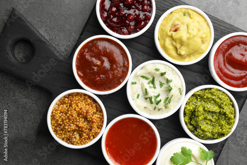 Different tasty sauces in bowls on grey table, top view