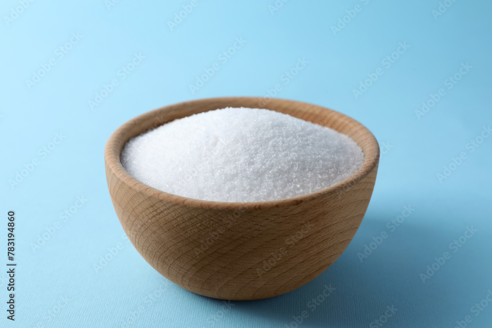Organic white salt in bowl on light blue background Organic white salt in bowl on light blue background