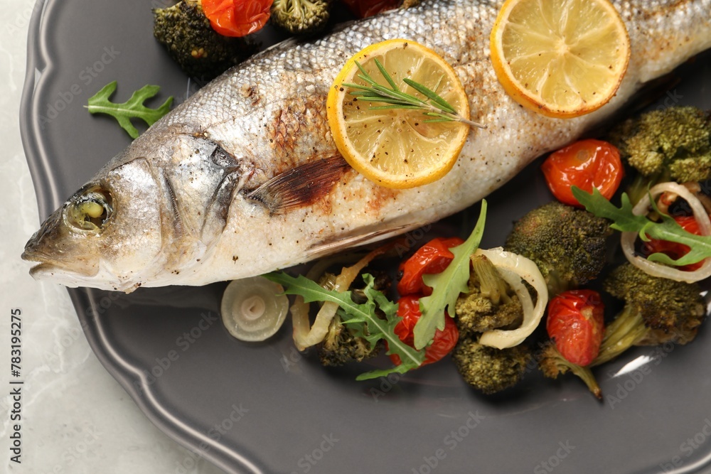 Baked fish with vegetables, rosemary and lemon on grey textured table, top view Baked fish with vegetables, rosemary and lemon on grey textured table, top view