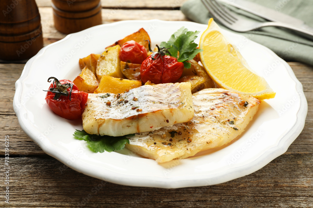 Tasty cod cooked with vegetables served on wooden table