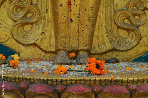 A scattering of raw rice grains and marigold flowers at the feet of a golden Hindu statue as a sacred religious ritual offering during Diwali photo