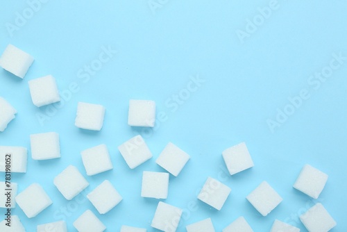 White sugar cubes on light blue background  top view. Space for text