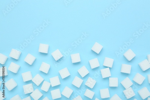 White sugar cubes on light blue background, top view. Space for text