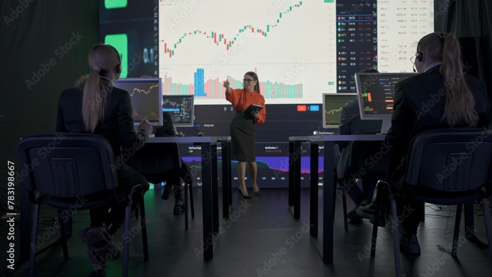 Successful business people in the office. Team of brokers and ceo top manager having meeting in front of big screens with charts talking selling stock.