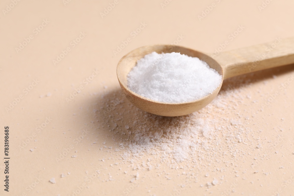 Natural salt with wooden spoon on beige background, closeup Natural salt with wooden spoon on beige background, closeup